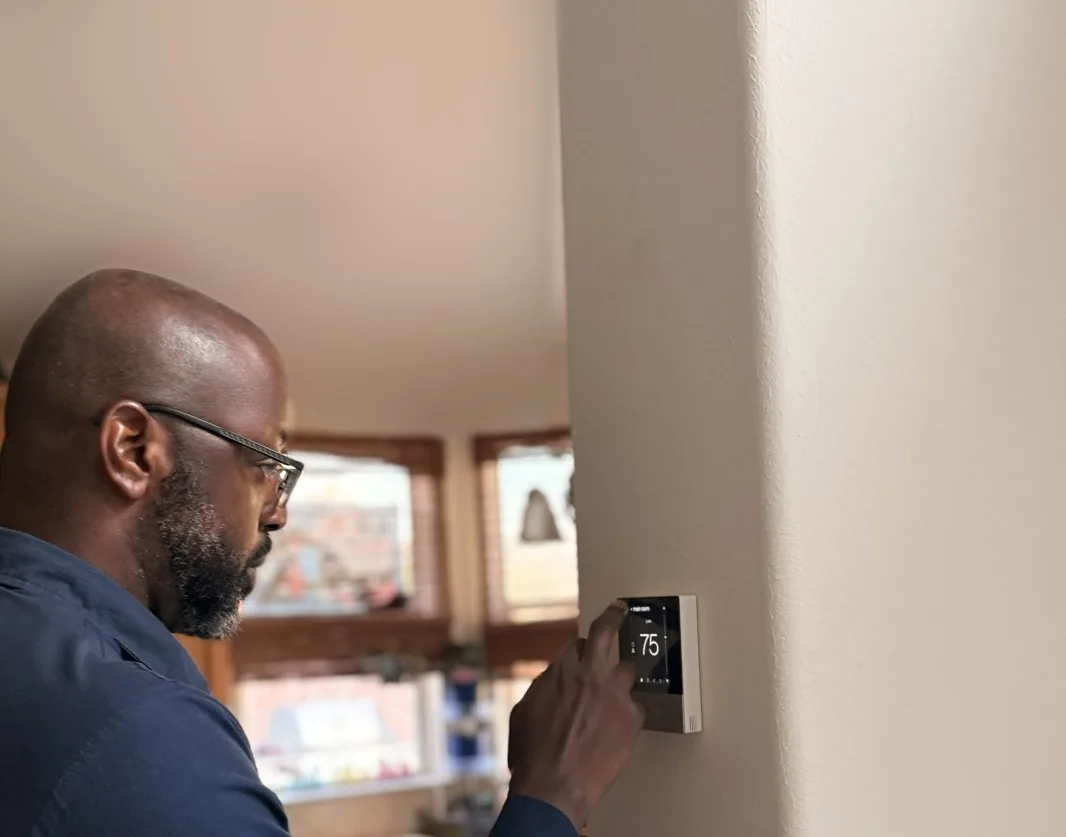 A technician from The General checks the reading on a wall-mounted thermostat in a Houston-area home.